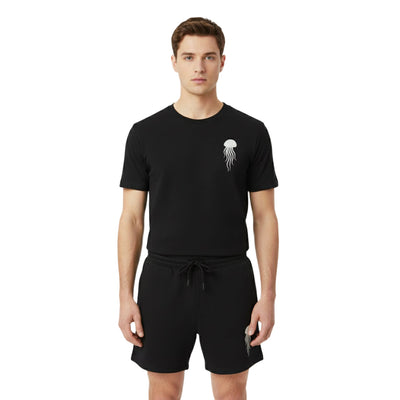 Man wearing a black t-shirt with a jellyfish design and black shorts on a white background