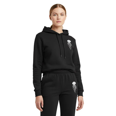 A woman wearing a black hoodie and pants with jellyfish designs on a white background