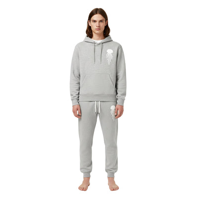 Person wearing a gray hoodie and pants with a logo on a white background