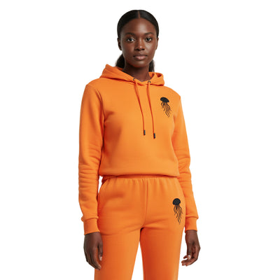 A woman wearing an orange hoodie and pants set with a jellyfish design on a white background