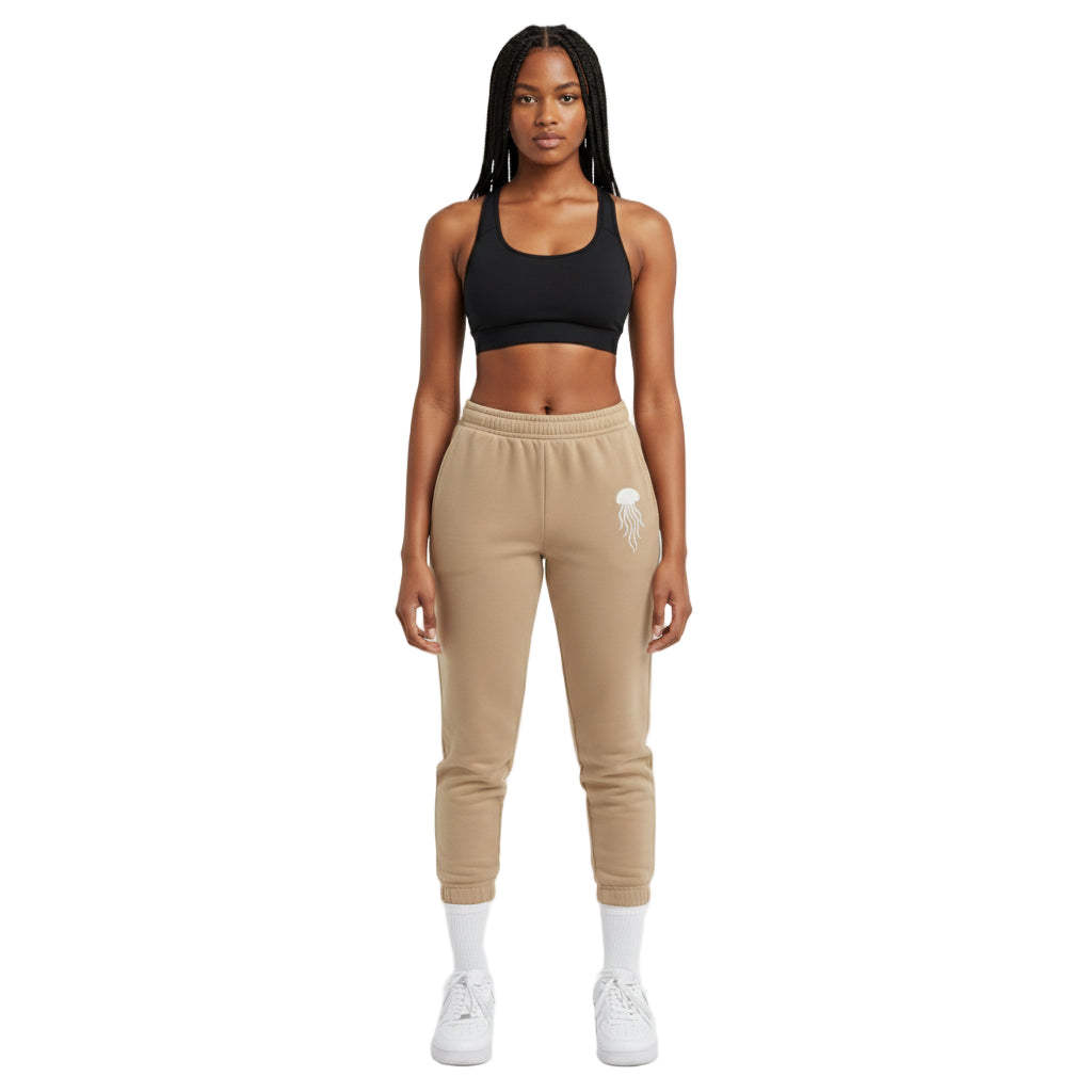 Woman wearing a black sports bra and beige jogger pants on a white background
