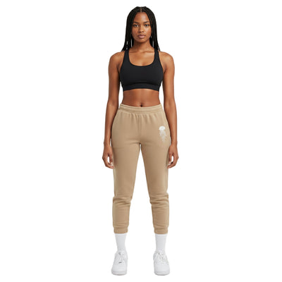 Woman wearing a black sports bra and beige jogger pants on a white background