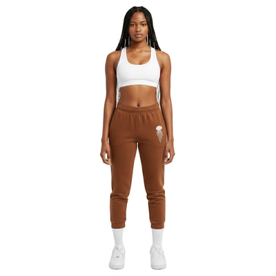 Woman wearing a white sports bra and brown sweatpants on a white background