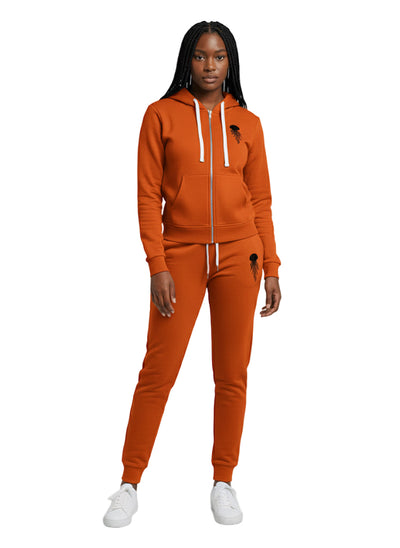 A woman wearing an orange stratosphere zip-up hoodie & jogger set with jellyfish logo in black color 